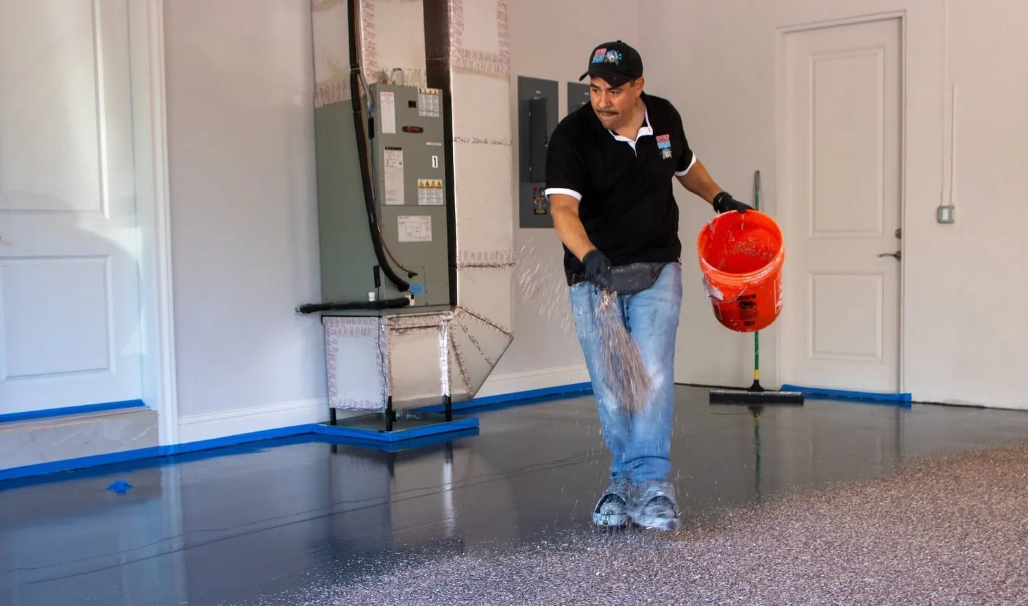 Applying flexible urethane caulk along an epoxy garage floor edge joint