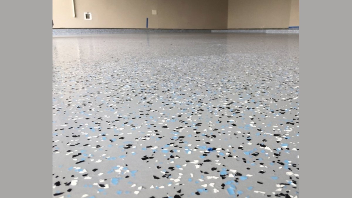 Freshly flake-coated garage floor with vinyl chips and a paint roller nearby