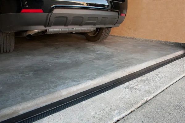 Peeling epoxy garage floor edge with water seeping under the coating